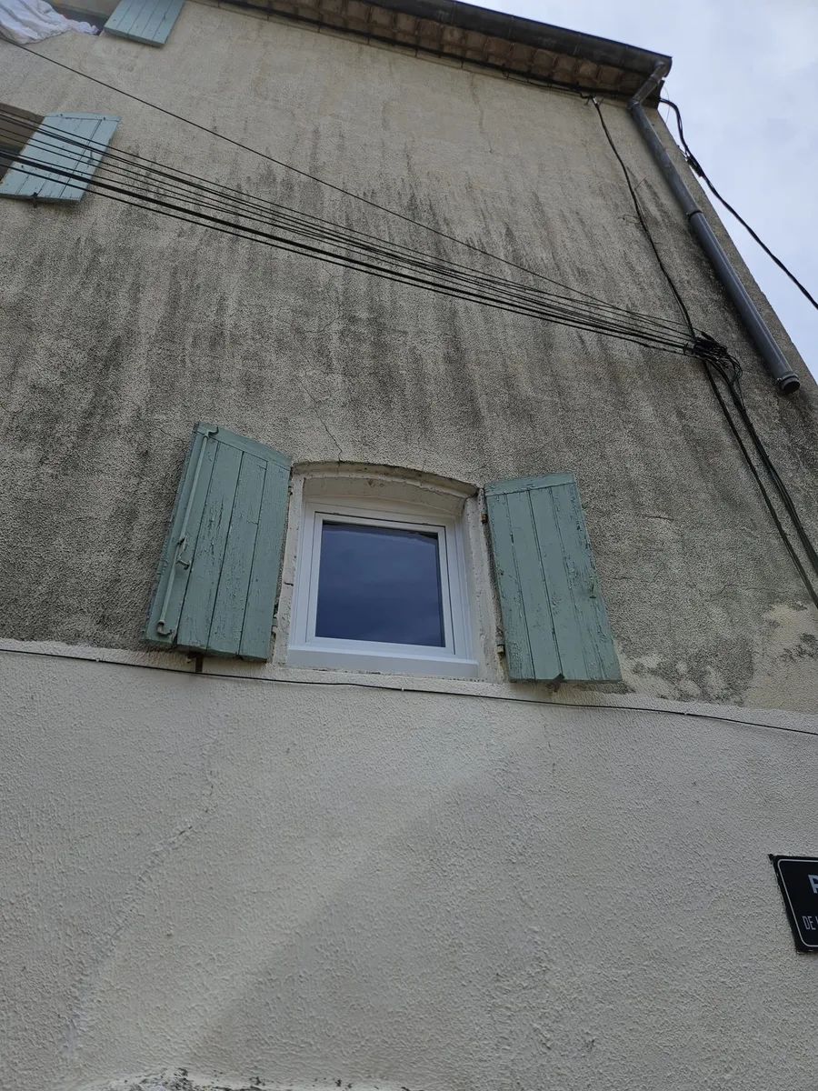Intérieur d'une fenêtre PVC blanche à double battant, offrant une vue sur le paysage et un balconnet à Dions.
